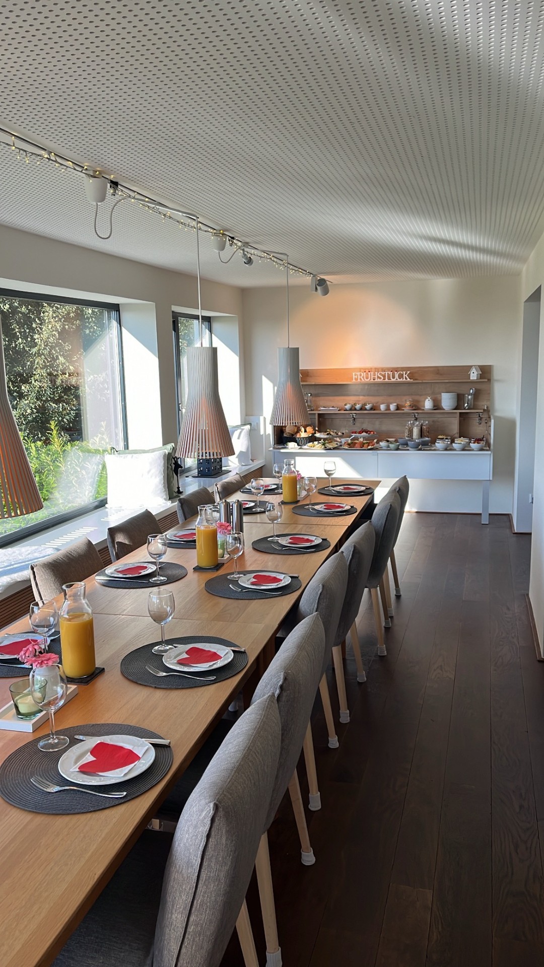 Eingedeckter Frühstückstisch mit Buffet im Hintergrund